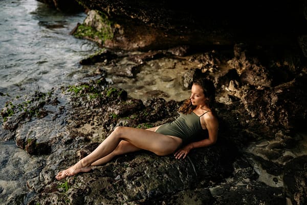 Relaxed lady resting on rocky coast near water